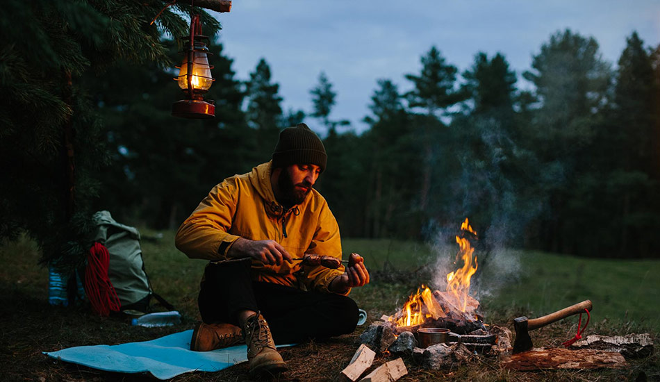 Man building a fire in the forest using ferro rod and natural tinder