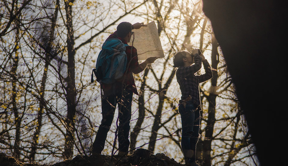 Camper setting up a tarp shelter in the woods